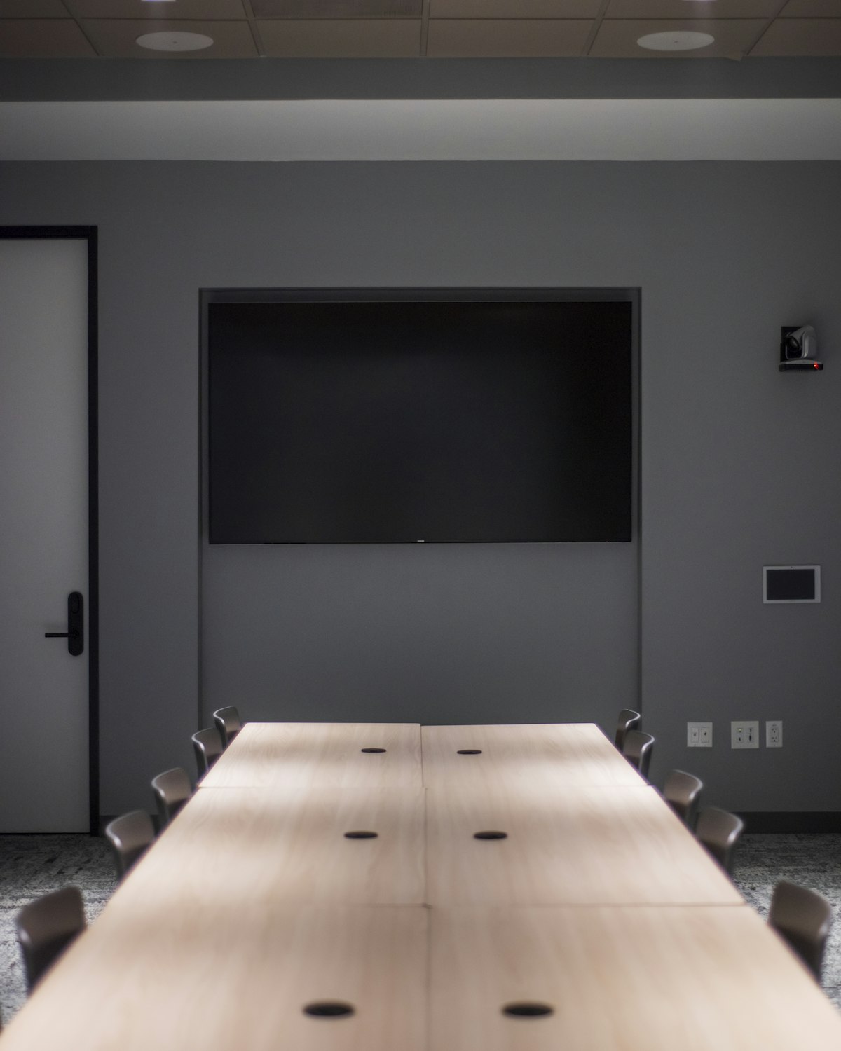 Empty boardroom with a long table and a wall screen